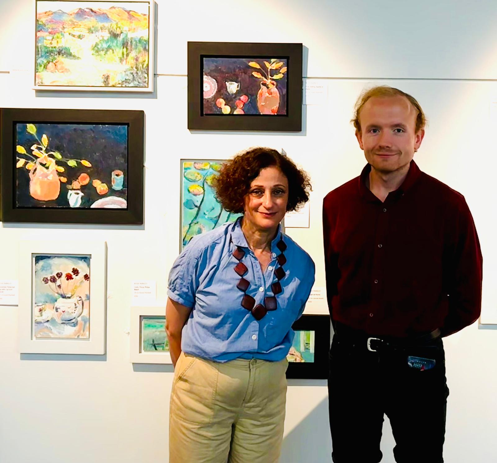 art curator John Reed and artist Rosie Parmley stand infront of art by artists from The Colour Factory.