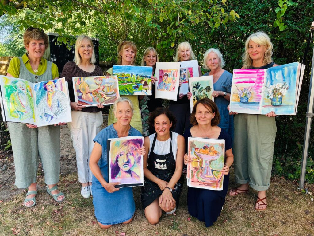 Bloomsbury summer school students holding up their sketchbooks in the garden studio