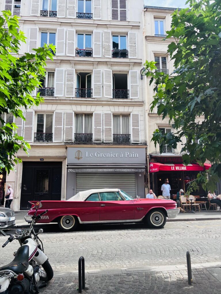 A vintage American car parked on a cobbled Montmartre street