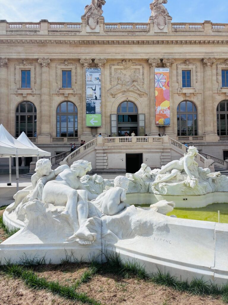 The Grand Palais facade with banners for the Hilma af Klint and Leandro Erlich exhibitions, Raoul Larche's fountain in front.